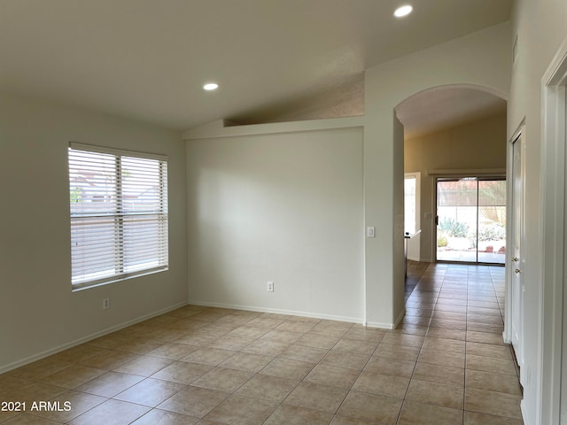 tiled spare room with a wealth of natural light and lofted ceiling