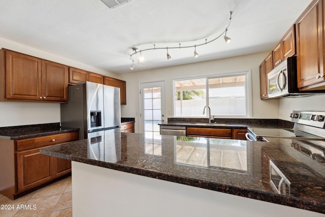 kitchen featuring dark stone counters, appliances with stainless steel finishes, sink, and kitchen peninsula