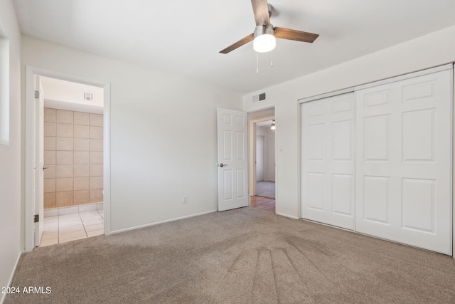 unfurnished bedroom with ceiling fan, light colored carpet, a closet, and ensuite bath