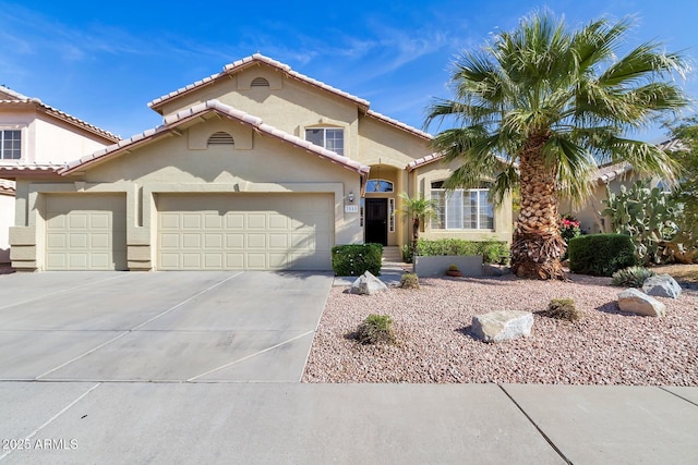 mediterranean / spanish-style home with a tiled roof, a garage, concrete driveway, and stucco siding