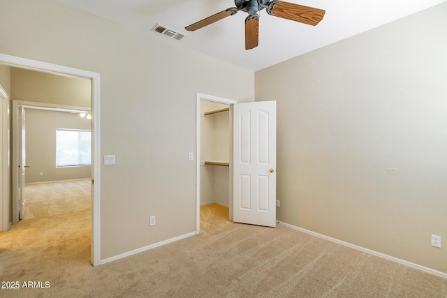 unfurnished bedroom featuring a spacious closet, visible vents, baseboards, light colored carpet, and a closet