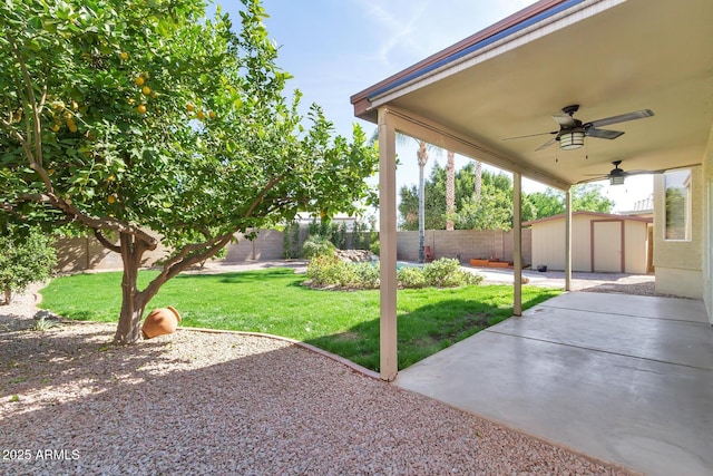 view of yard featuring an outbuilding, a ceiling fan, a patio, a fenced backyard, and a shed