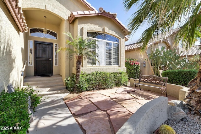 doorway to property with a tile roof and stucco siding