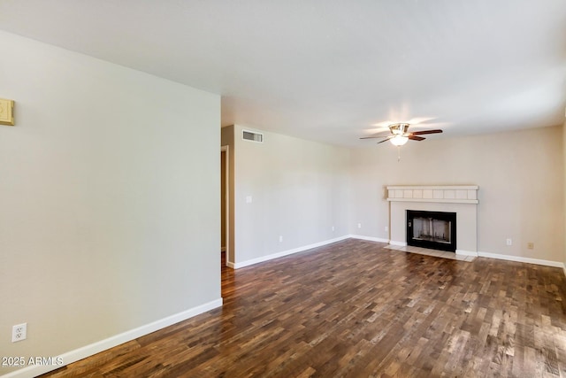 unfurnished living room featuring dark wood-type flooring, a ceiling fan, visible vents, and baseboards