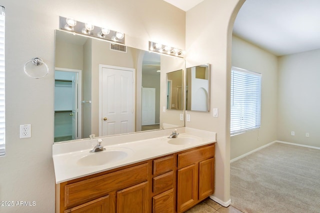 bathroom with a sink, visible vents, baseboards, and double vanity