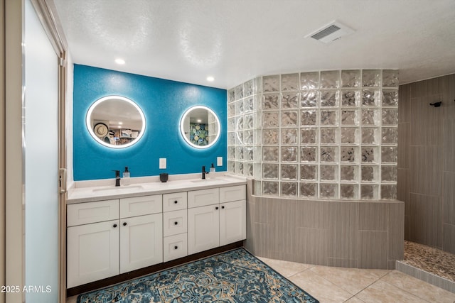 full bathroom with a walk in shower, visible vents, tile walls, and a sink