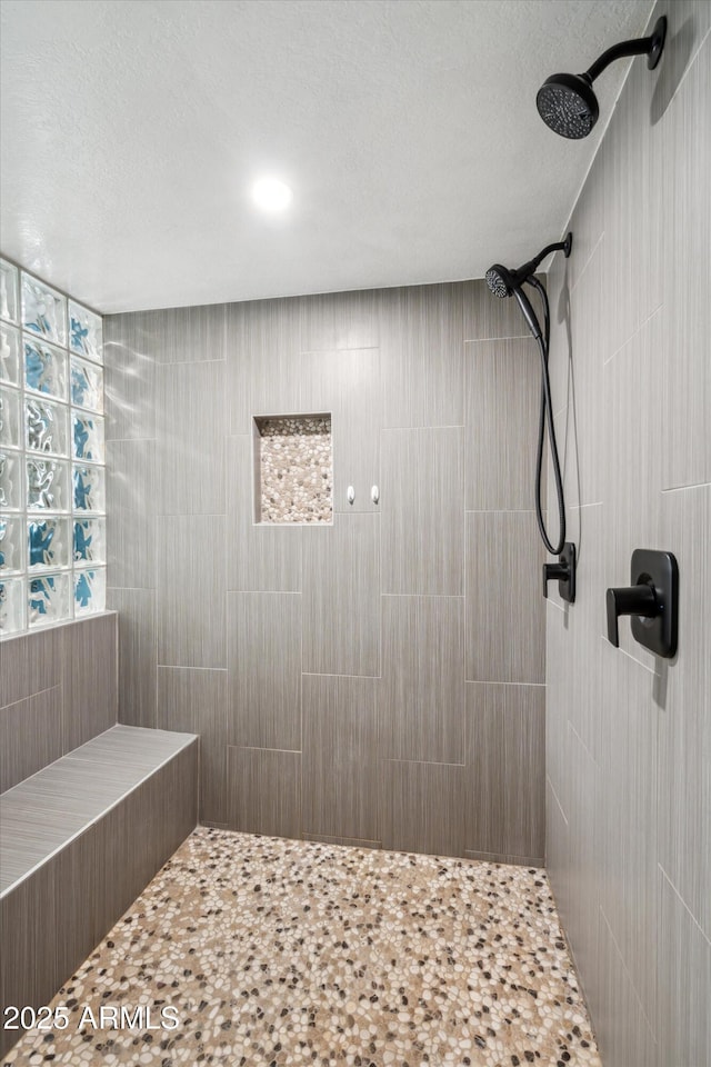 bathroom featuring a textured ceiling and tiled shower
