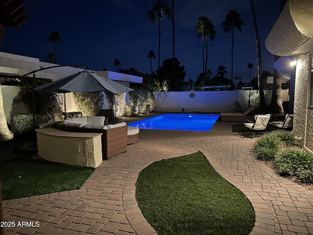 pool at twilight with a fenced backyard, a fenced in pool, a patio, and an outdoor hangout area