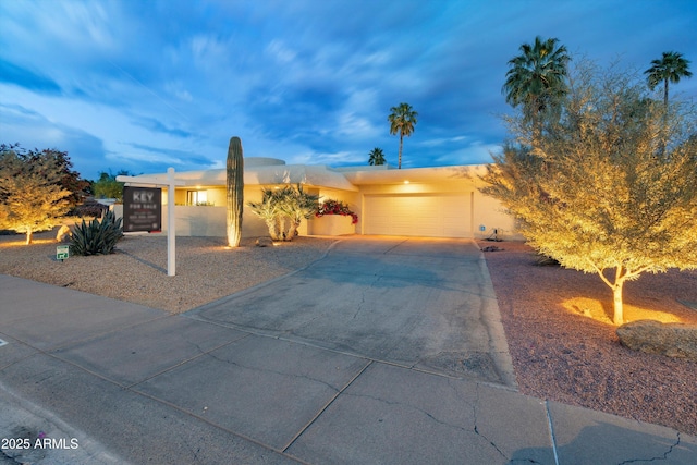 ranch-style house with a garage, stucco siding, and driveway