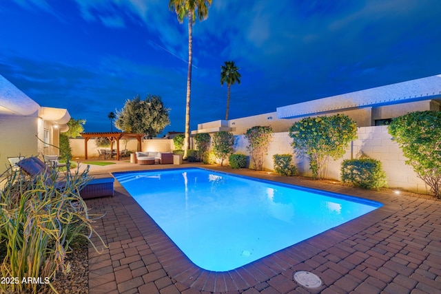 pool at night featuring an outdoor hangout area, a pergola, a patio area, and a fenced backyard