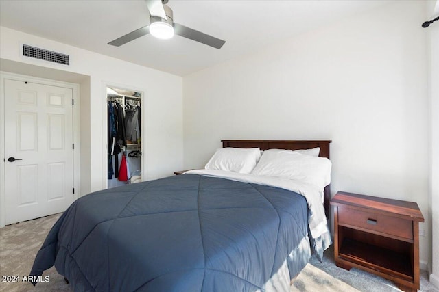 carpeted bedroom featuring a walk in closet, a closet, and ceiling fan