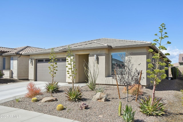 prairie-style home featuring a tiled roof, a garage, driveway, and stucco siding