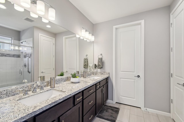 bathroom with a sink, baseboards, a stall shower, and double vanity