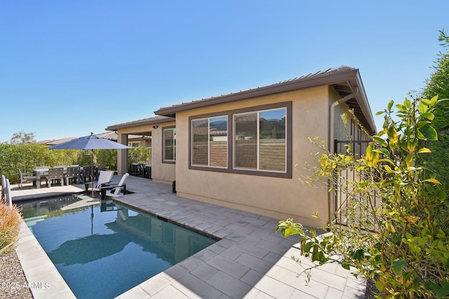 rear view of house featuring a patio area, a fenced in pool, and stucco siding