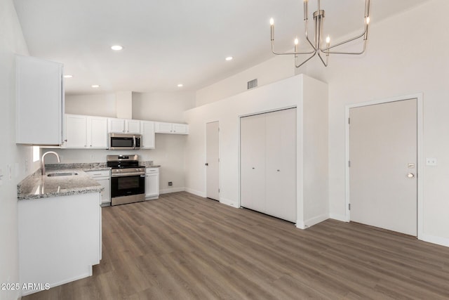 1727 W 12th Ave, Apache Junction, AZ 85120 - kitchen featuring appliances with stainless steel finishes, white cabinetry, vaulted ceiling, wood finished floors, and a chandelier