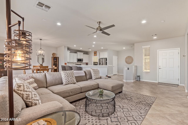 living room featuring light tile patterned flooring and ceiling fan with notable chandelier