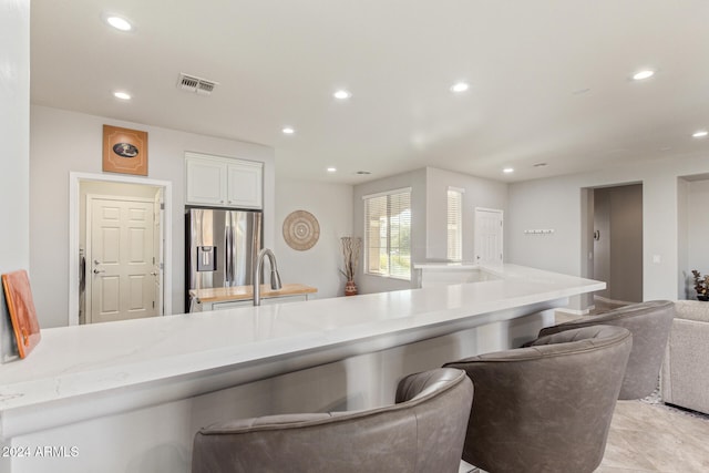 kitchen with white cabinets, sink, light tile patterned floors, and stainless steel refrigerator with ice dispenser