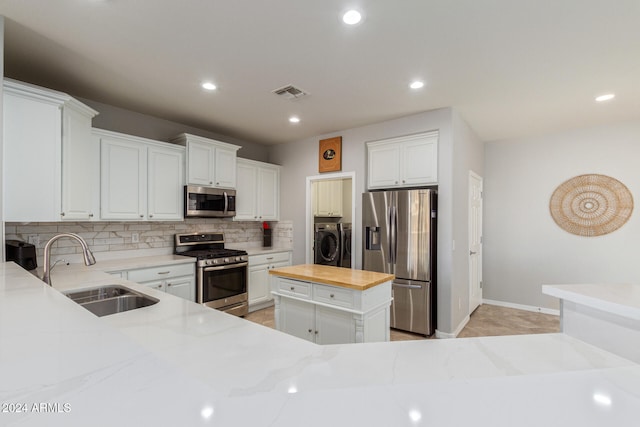 kitchen with appliances with stainless steel finishes, a center island, white cabinetry, and butcher block counters