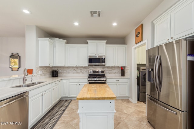 kitchen featuring a center island, sink, stainless steel appliances, wood counters, and washing machine and dryer