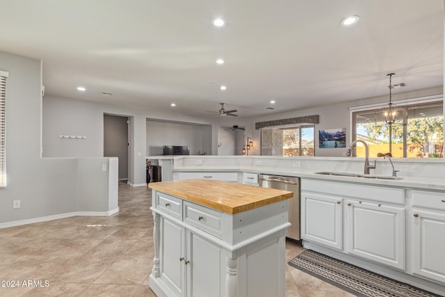 kitchen featuring sink, wood counters, a kitchen island, stainless steel dishwasher, and white cabinets