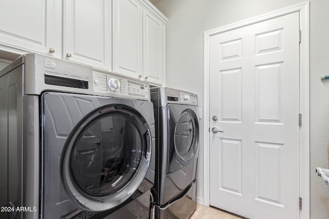 washroom featuring cabinets and washer and clothes dryer