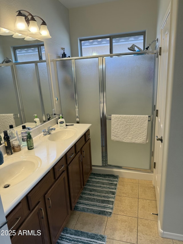 bathroom with tile patterned flooring, a shower stall, double vanity, and a sink