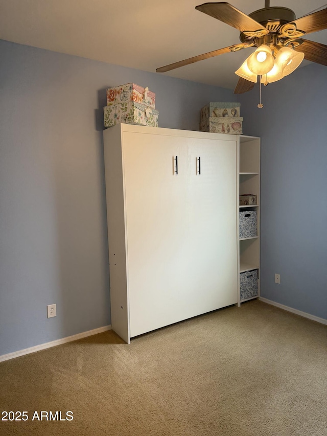 carpeted empty room featuring baseboards and ceiling fan