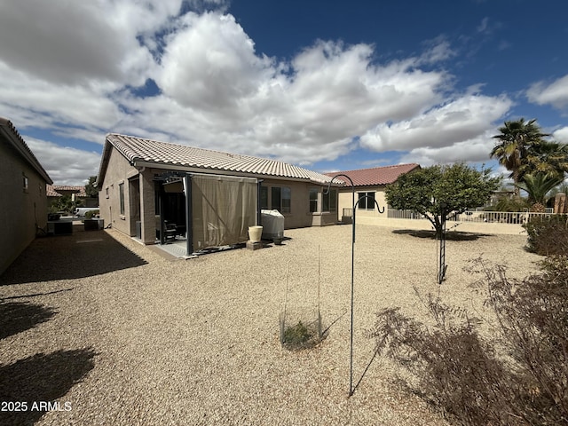 rear view of property with stucco siding, fence, a patio area, and a tile roof