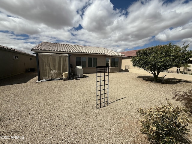 rear view of property with stucco siding, central AC, and a tiled roof