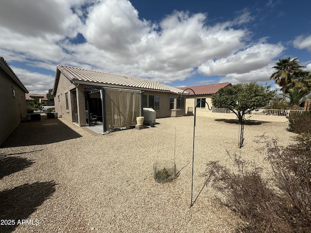 back of property featuring a tile roof, a patio area, fence, and stucco siding