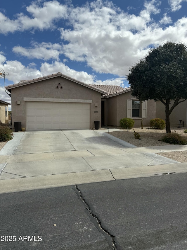 view of front of house featuring a tile roof, stucco siding, concrete driveway, and a garage