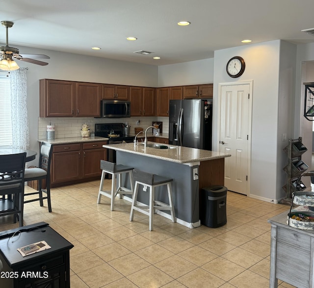 kitchen featuring visible vents, a sink, tasteful backsplash, appliances with stainless steel finishes, and light tile patterned flooring