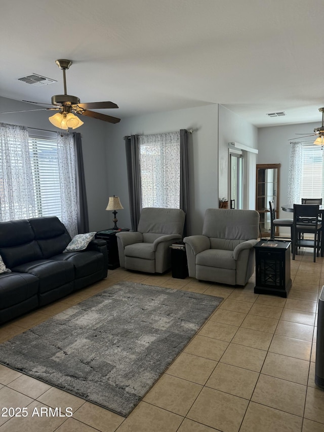 living area featuring light tile patterned floors, visible vents, and ceiling fan