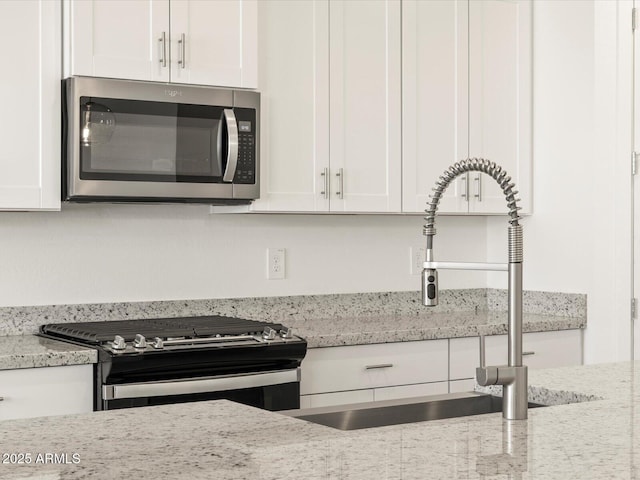 kitchen featuring light stone countertops, white cabinets, sink, and stainless steel appliances