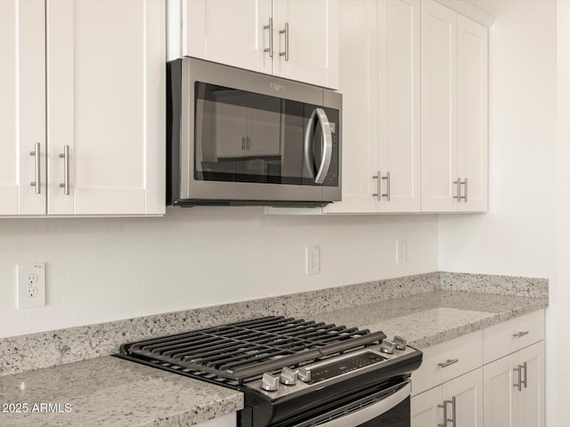 kitchen featuring appliances with stainless steel finishes, white cabinetry, and light stone countertops