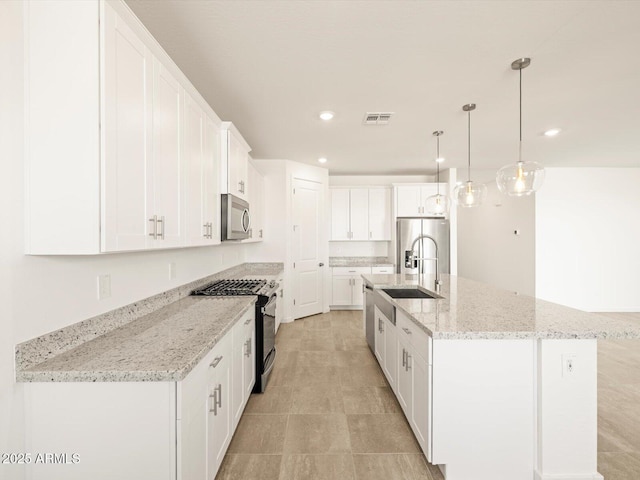 kitchen featuring white cabinetry, stainless steel appliances, a center island with sink, and hanging light fixtures