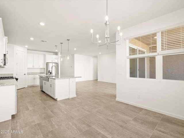 kitchen featuring decorative light fixtures, sink, a kitchen island with sink, stainless steel appliances, and white cabinets