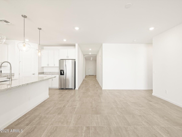 kitchen featuring pendant lighting, sink, white cabinetry, light stone countertops, and stainless steel fridge with ice dispenser