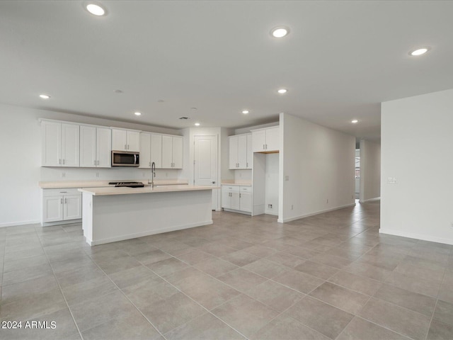 kitchen featuring a kitchen island with sink and white cabinetry