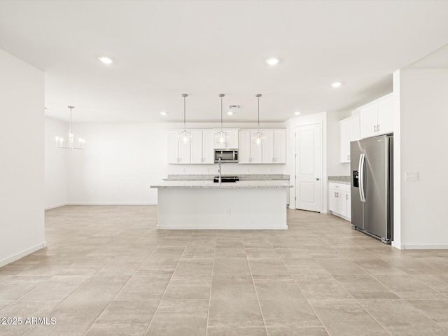 kitchen featuring appliances with stainless steel finishes, white cabinets, hanging light fixtures, and an island with sink