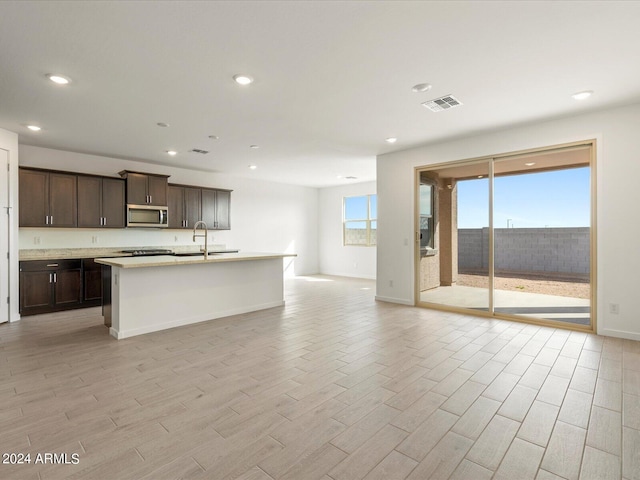 kitchen with sink, a center island with sink, and dark brown cabinets