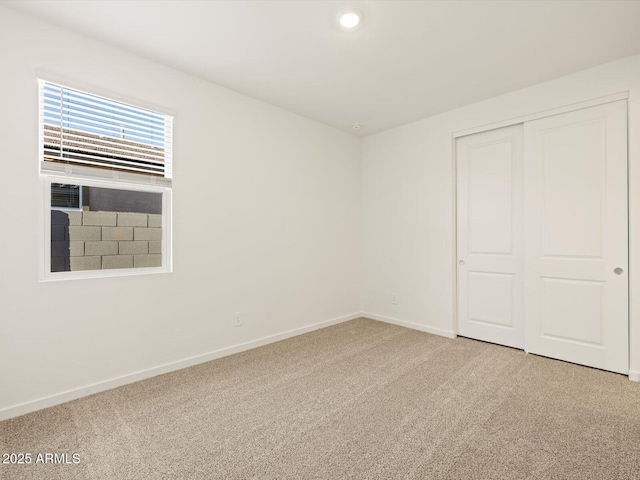 unfurnished bedroom with a closet and light colored carpet