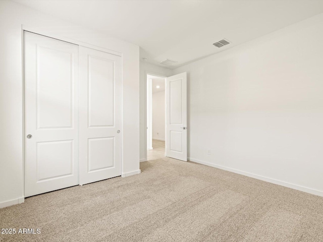 unfurnished bedroom featuring light colored carpet and a closet