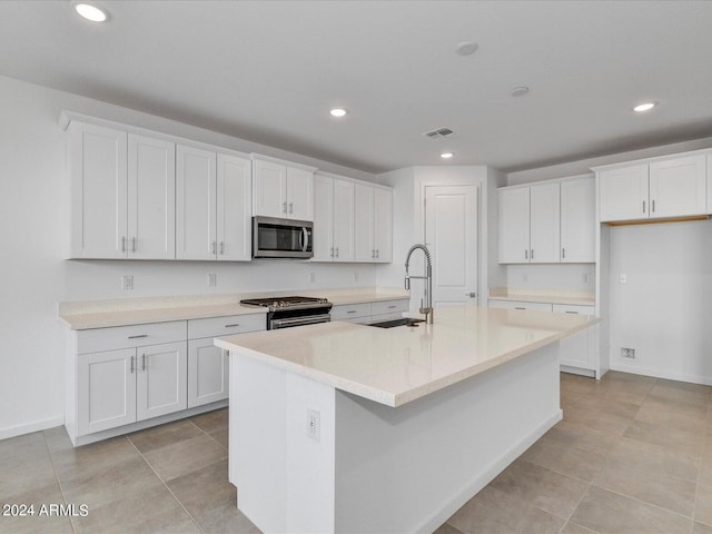 kitchen with white cabinets, a kitchen island with sink, appliances with stainless steel finishes, and sink