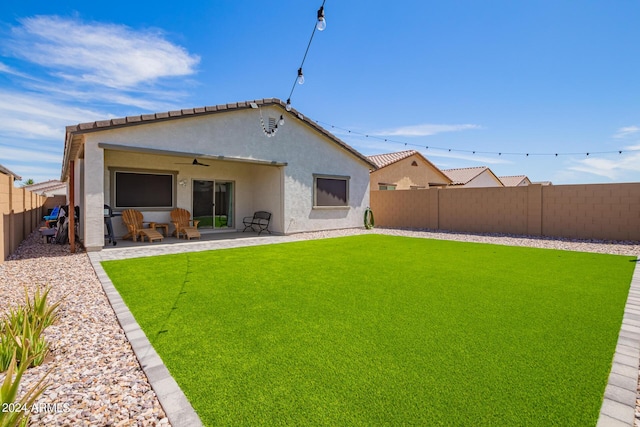 rear view of property with a patio area, ceiling fan, and a yard