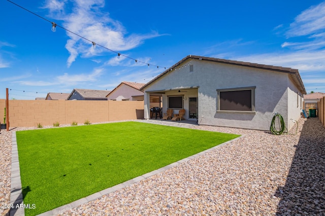 back of property with ceiling fan, a yard, and a patio