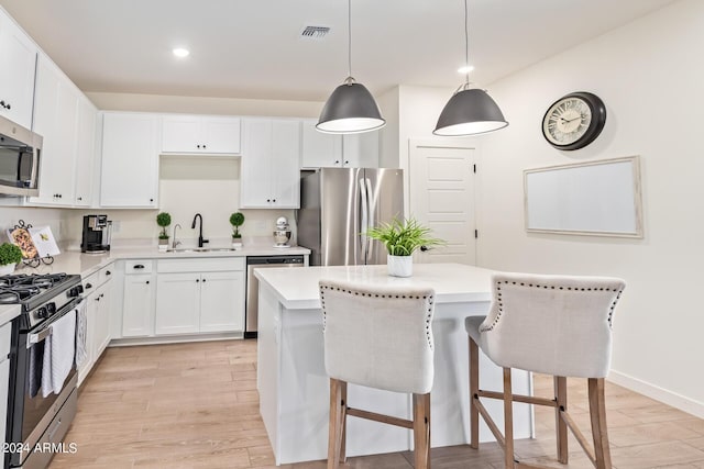 kitchen featuring pendant lighting, sink, light hardwood / wood-style flooring, appliances with stainless steel finishes, and a kitchen island