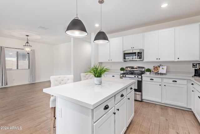 kitchen with a center island, stainless steel appliances, decorative light fixtures, white cabinets, and light wood-type flooring