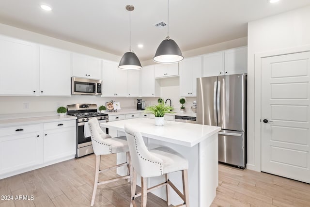 kitchen with appliances with stainless steel finishes, a center island, decorative light fixtures, and white cabinetry