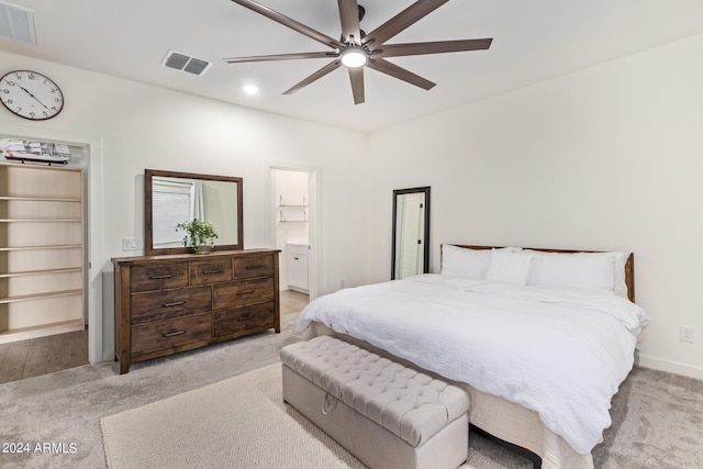 carpeted bedroom with ceiling fan and a walk in closet